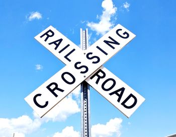 Low angle view of road sign against blue sky