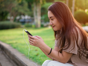 Young woman looking at camera while using mobile phone