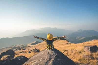 Rear view of man standing on mountain against sky