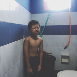 Young man looking away while sitting in bathroom