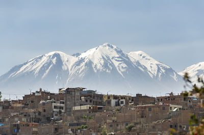 Townscape against snowcapped mountain against sky