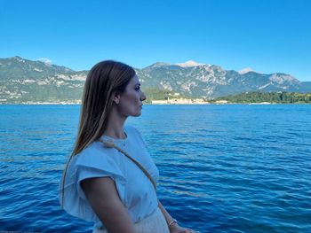 Side view of young woman against blue sea