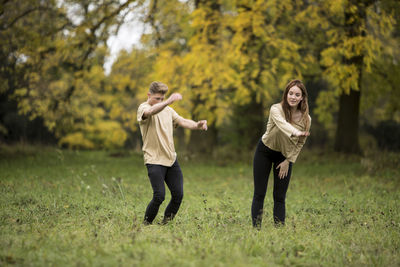 Young couple dancing on grassy field at park
