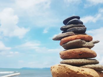 Stack of stones on beach against sky