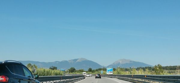 Road by mountain against blue sky