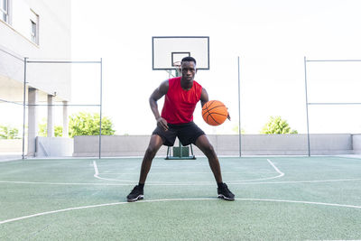 Serious african american male playing basketball on modern sports ground and looking at camera during training