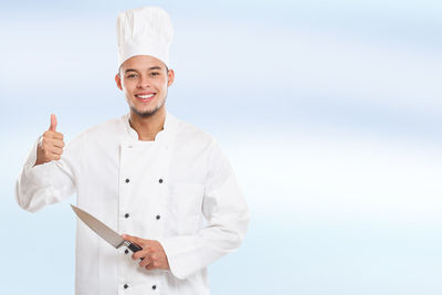 Portrait of a smiling young man standing against clear sky