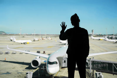 Rear view of man standing on airplane against sky