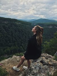 Rear view of woman standing on mountain against sky