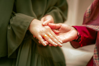 Midsection of couple holding hands, engagement day