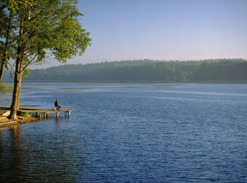 Men fishing in lake against sky