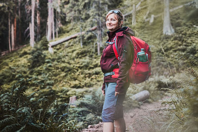 Woman with backpack hiking in mountains, spending summer vacation close to nature