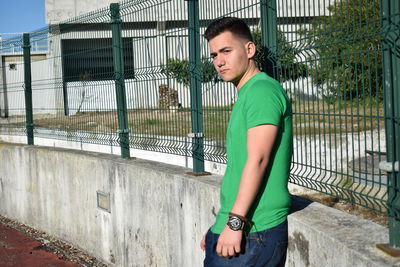 Portrait of young man standing by railing