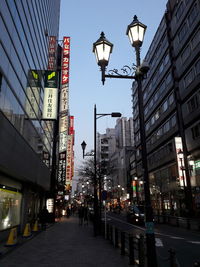 Illuminated street lights in city against sky