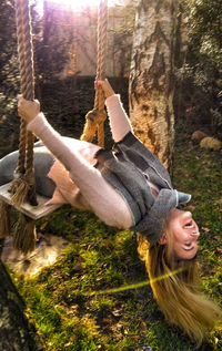 Happy woman with arms raised on tree