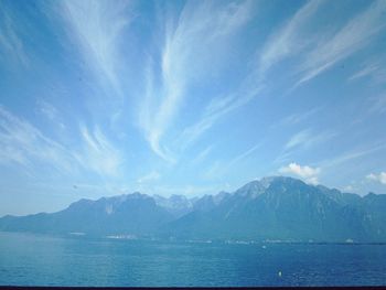 Scenic view of sea and mountains against blue sky