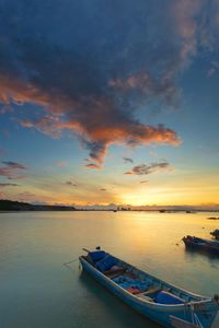 Boat moored on sea against sky during sunset