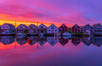 Reflection of buildings in lake against sky during sunset