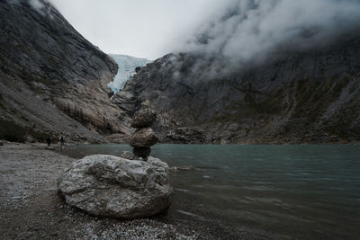 Rock formation by lake against sky