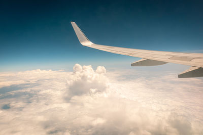 Airplane flying above the clouds at sunset.