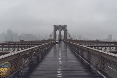 Crossing the brooklyn bridge with stormy rain cloud mist over skyline.
