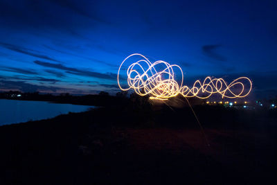 Illuminated light trails against sky at night