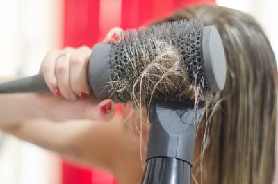 Close-up of woman drying hair with dryer