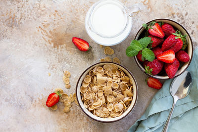 Healthy breakfast - whole grain flakes, milk and fresh strawberries on stone or slate background. 