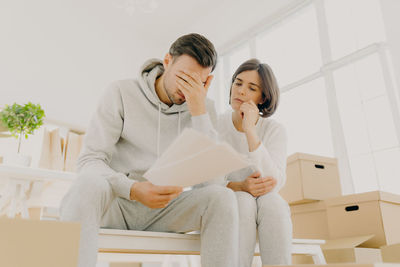 Woman sitting with stressed man by boxes at home