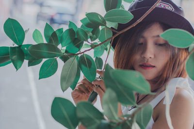 Portrait of young woman standing by plants