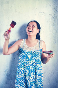 Smiling young woman standing against wall