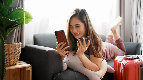 Smiling woman online shopping though mobile phone at home