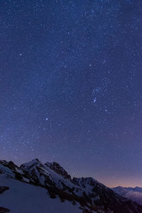 Scenic view of snowcapped mountains against sky at night