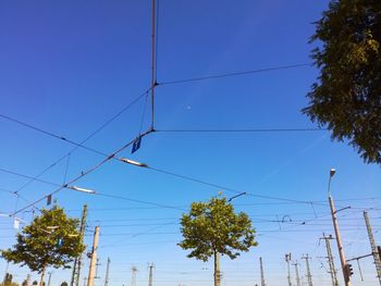 Low angle view of electricity pylon against clear blue sky