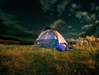 People resting on grassy field against cloudy sky