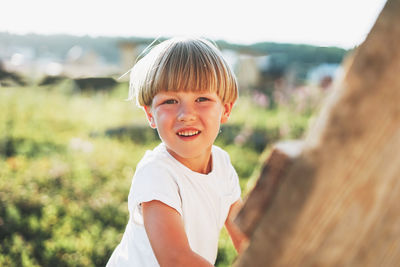 Cute blonde toddler boy climbs up ladder, country side, cottagecor