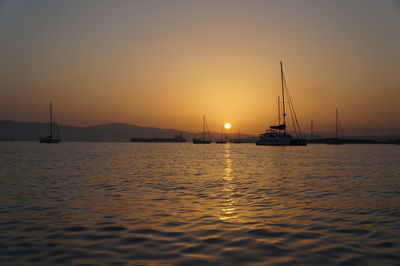 Boats sailing in sea at sunset