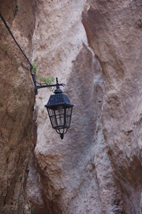 Low angle view of electric lamp hanging on rock