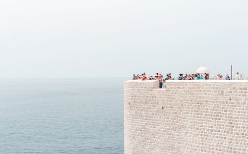 People at fort over adriatic sea against sky