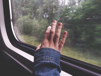 Cropped image hand by train window