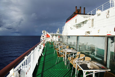 Empty chairs and tables arranged in ship on sea