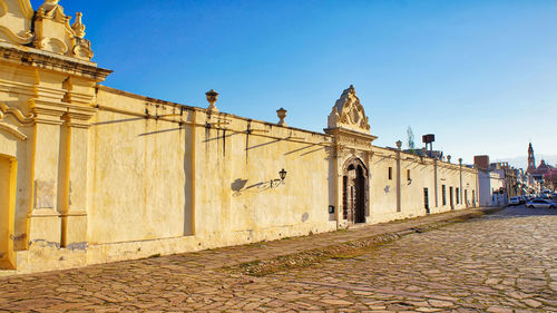 Street amidst buildings against clear blue sky