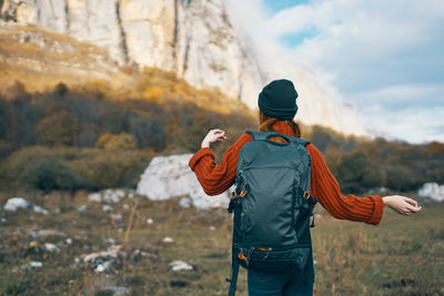 Rear view of man standing on rock against sky