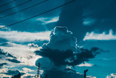 Low angle view of silhouette cables against blue sky