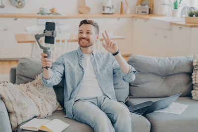 Young man using mobile phone while sitting on sofa at home