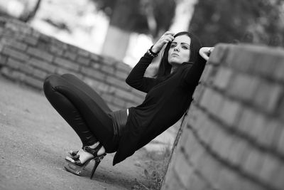 Woman looking away while crouching against wall