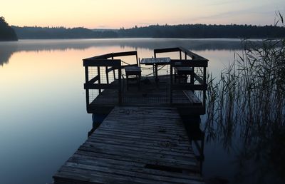 Pier on lake against sky during sunset