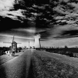 Road by factory against sky