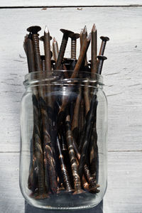 Close-up of rusty screws in glass jar on table