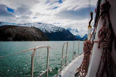 Boats sailing on sea by mountains against sky